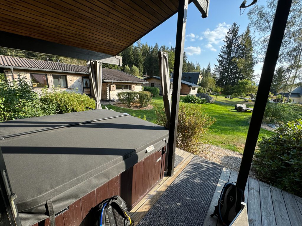 Abgedeckter Whirlpool auf einer überdachten Terrasse mit Blick über das Resortgelände