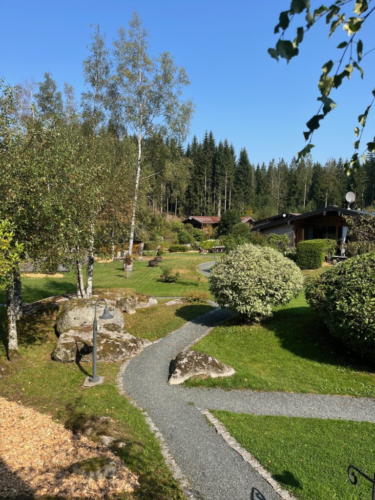 Kiesweg durch die Gartenanlage des Hüttenresorts Mare, umgeben von Birken und Nadelwald