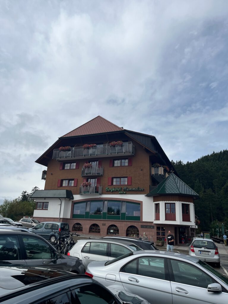 Das Berghotel Mummelsee von der Parkplatzseite aus, im Hintergrund bewaldete Hänge